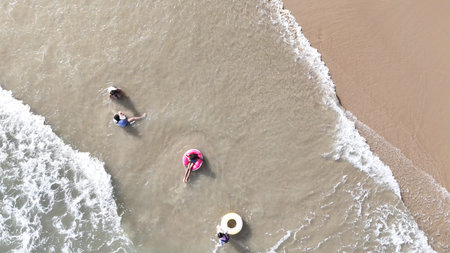 Happy children playing together in the sea, enjoying a fun summer day at the beach with laughter and...