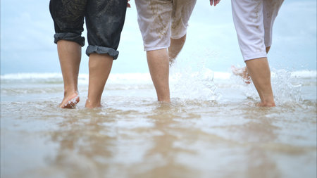Foots of senior women enjoying a playful on the beach, happy as they splash through the waves