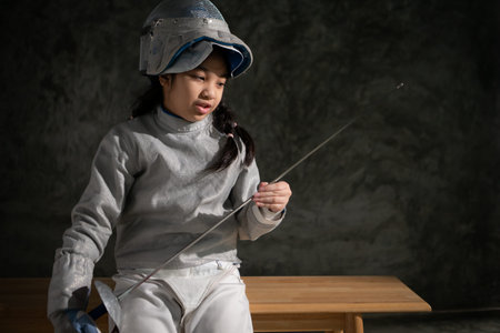 A girl in fencing gear sitting on a bench, ready for the Ã©pÃ©e competition