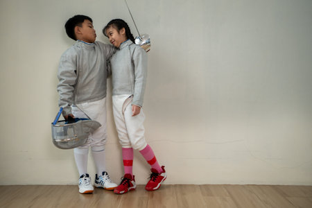 Before the tournament day, a boy and girl dressed in fencing gear are rehearsing in gym