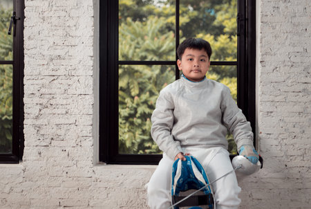 Before the tournament day, a boy dressed in fencing gear are rehearsing in gym