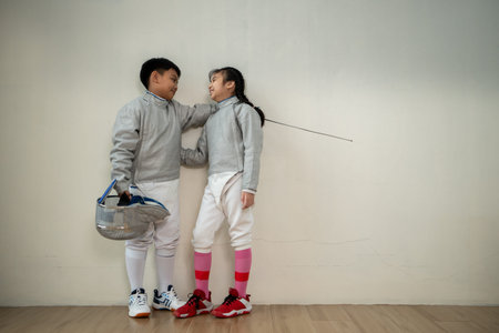 Before the tournament day, a boy and girl dressed in fencing gear are rehearsing in gym