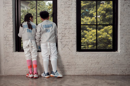 Before the tournament day, a boy and girl dressed in fencing gear are rehearsing in gym