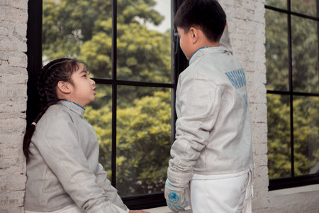 Before the tournament day, a boy and girl dressed in fencing gear are rehearsing in gym