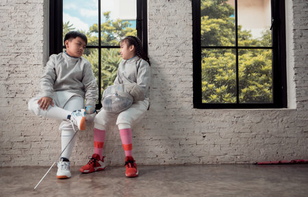 Before the tournament day, a boy and girl dressed in fencing gear are rehearsing in gym