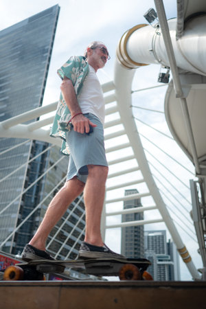 Senior man riding an electric skateboard in the city, enjoying urban lifestyle with modern architecture and skyscrapers in the backgroundの写真素材