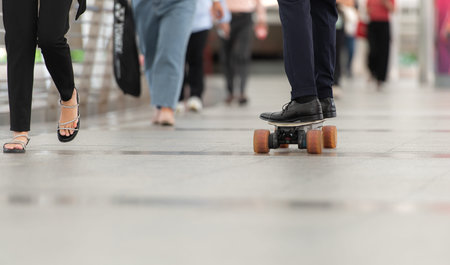 Senior businessman in a suit riding an electric skateboard in the city, enjoying urban lifestyle...