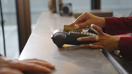 Customer making payment at hotel reception using credit card terminal, close-up of transaction...