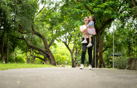 Mother and daughter jogging together in the park, promoting healthy lifestyle and family bondingの写真素材