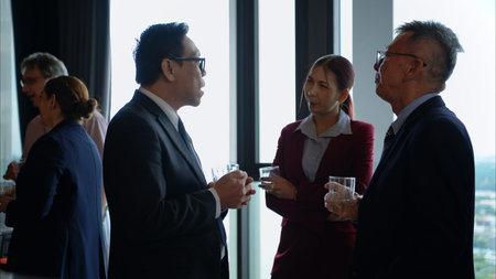 Business professionals networking and enjoying drinks at a corporate event in a modern office...