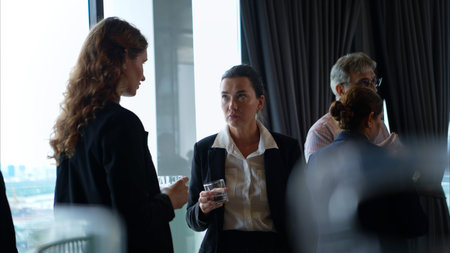 Business professionals networking and enjoying drinks at a corporate event in a modern office...