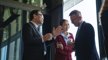 Business professionals networking and enjoying drinks at a corporate event in a modern office...