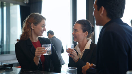 Smiling bartender serving drinks to customers at a modern bar with a stylish liquor displayの写真素材