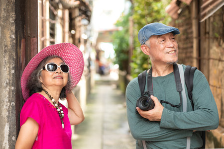 A happy senior couple strolling along a city's old neighborhood, enjoying travel, street exploration, and cultural adventure with smiles and relaxed momentsの写真素材
