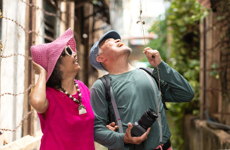 A happy senior couple strolling along a city's old neighborhood, enjoying travel, street exploration, and cultural adventure with smiles and relaxed momentsの写真素材