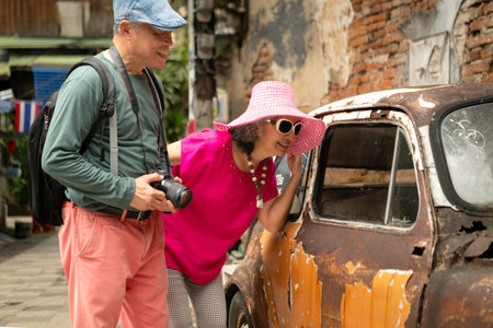 A happy senior couple strolling along a city's old neighborhood, enjoying travel, street exploration, and cultural adventure with smiles and relaxed momentsの写真素材