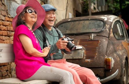 A happy senior couple strolling along a city's old neighborhood, enjoying travel, street exploration, and cultural adventure with smiles and relaxed momentsの写真素材