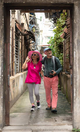 A happy senior couple strolling along a city's old neighborhood, enjoying travel, street exploration, and cultural adventure with smiles and relaxed momentsの写真素材