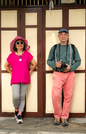 A happy senior couple strolling along a city's old neighborhood, enjoying travel, street exploration, and cultural adventure with smiles and relaxed momentsの写真素材