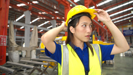 Young woman experienced technician checking large machine on a production line at an industrial...