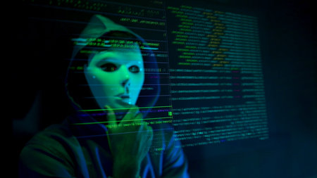 Anonymous hacker wearing a mask and hoodie interacting with digital data in a dark room,...