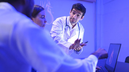 Doctors and medical professionals discussing heart health with futuristic hologram technology in a...