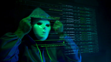 Anonymous hacker wearing a mask and hoodie interacting with digital data in a dark room,...
