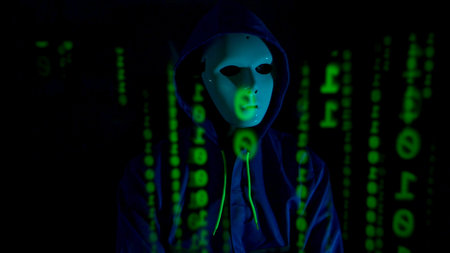 Anonymous hacker wearing a mask and hoodie interacting with digital data in a dark room,...