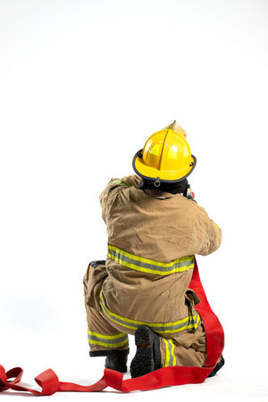 Full-body studio portrait of a firefighter in protective uniform holding a firefighting and fire hose nozzle. The individual stands confidently against a white backgroundの写真素材