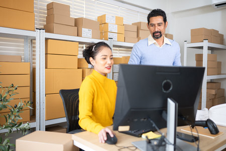 Small business team checking inventory together in warehouse with shelves full of parcels and boxes