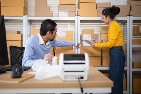 Warehouse manager pointing at inventory shelves while staff checks stock list on tablet during...