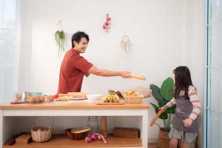 A father and daughter playfully sword-fight with baguettes in the kitchen, creating a fun and lively...