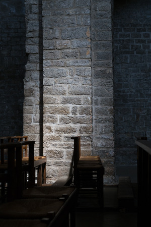 Wooden Chairs in a Dark Church, Subtle Lighting on Stone Wallの写真素材