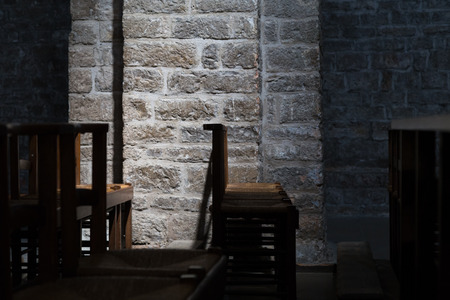Wooden Chairs in a Dark Church, Subtle Lighting on Stone Wallの写真素材