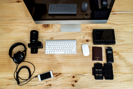 Office computer PC camera, mobile phone, headphone,sound recorder,passport,memory card,keyboard and mouse on wooden deskのeditorial素材