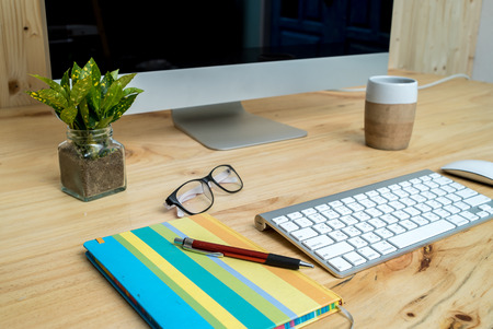 Office desk table with computer, supplies and coffee cup, white blank notepad, cup, pen, pc, Spectacles on wooden background. Closeupのeditorial素材