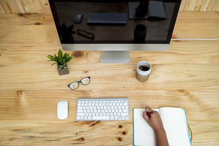 Office computer PC, coffee cup, keyboard and mouse on wooden desk, Asian women hands are working. View from aboveのeditorial素材