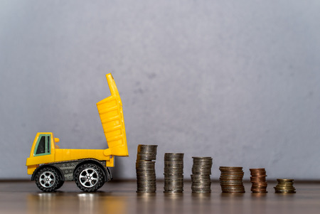 business and money concept - Dump truck toy downloading a coins stackの写真素材