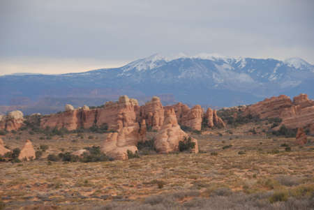 Natural stone wall cliff stand in front of high mountains covered with snowの写真素材