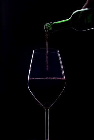 Red wine poured into a glass on a black backgroundの写真素材