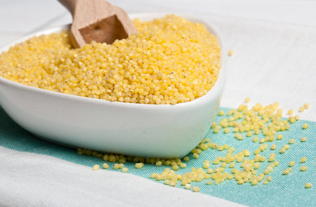 Millet groats in white bowl on kitchen towel