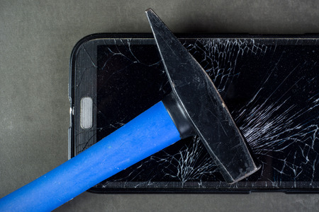 Smartphone with broken glass and hammer on gray backgroundの写真素材