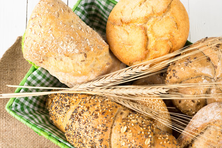 Wooden table with bread rolls in green basket