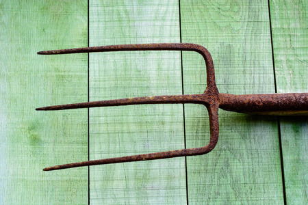Old rusty pitchfork on green wooden planksの写真素材