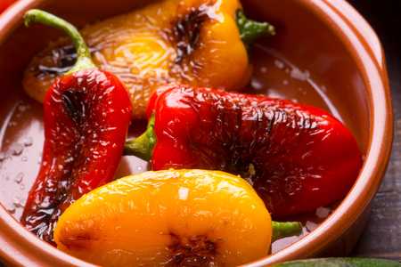 Red and yellow grilled peppers with salt in brown bowlの写真素材