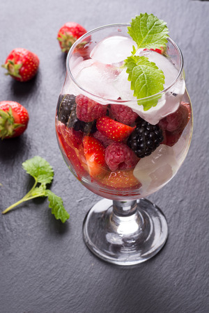 Glass with cold drink with ice and mixed soft fruitsの写真素材