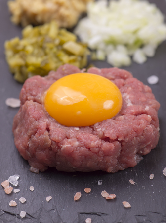 Fresh home made tartare beef steak with egg yolk on black slate plateの写真素材