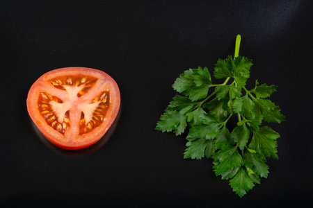 Tomato and green celery on black plate - vegan food. Top view.