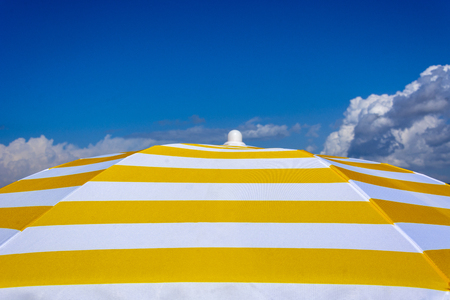 White and yellow sun umbrella on blue sky. Summer holidayの写真素材