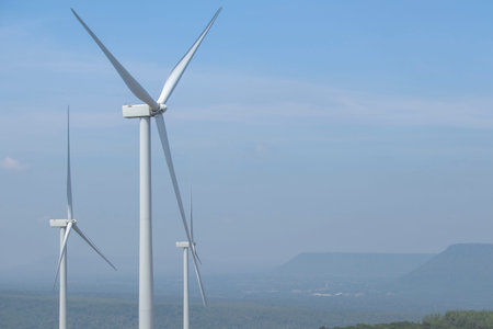 Wind turbine for electricity generation Behind the mountains in the sky there are white clouds on a...